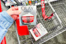 person placing olay moisturizer in a cart