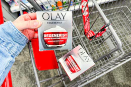 person placing olay moisturizer in a cart