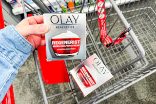 person placing olay moisturizer in a cart