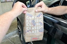 a person handing a sonic bag to a person to a person sitting in a car