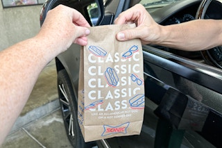 a person handing a sonic bag to a person to a person sitting in a car