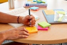 Person writing on Post-it Sticky Notes