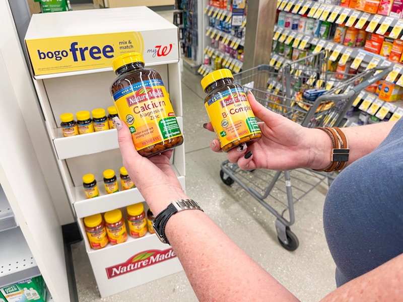 someone holding vitamins in front of bogo free sign