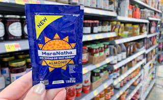 small blue packet of maranatha almond butter held up in front of walmart aisle