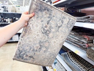 In store photo of the Mainstays Persian accent rug (held up)