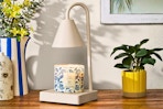 Lifestyle image of the Mainstays Candle Warmer Lamp used to heat up a candle in home setting