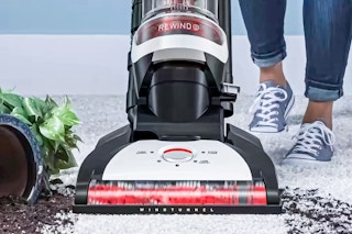 Lifestyle image of the Hoover Windtunnel Vacuum being used to clean up spilt soil from a fallen over plant