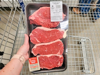 hand holding a pack of steaks