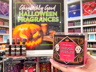 hand holding Halloween three-wick-candle in front of display