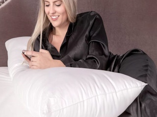 a woman on a bed with a body pillow