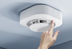 a person touching a button on a smoke alarm