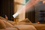 woman lying on bed next to mini projector