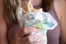 A person holding a Taco Bell burrito with a bite taken out of it.
