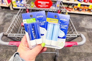 person holding 2 2-packs of nivea lip balm over a cart