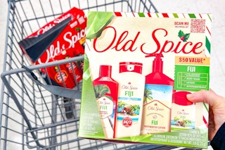 person holding an old spice gift set over a cart with another gift set in it