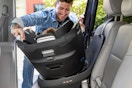 a dad putting a child into a rotational evenflo car seat