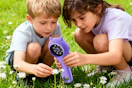 two kids sharing a microscope outside