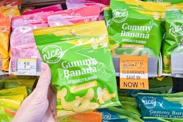 person holding a bag of peelable candy by a clearance sign for $1