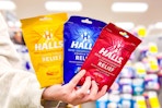 person holding 3 bags of halls cough drops