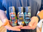 3 Axe Body Sprays held in men's hands (close up shot)