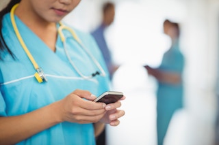 A nurse holds a smartphone.