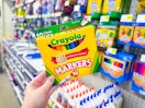 a hand holding a pack of Crayola markers in a store