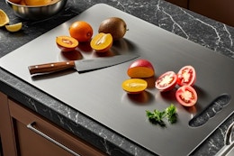 Titanium cutting board with knife and fruit on it.