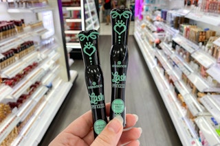 A person's hand holding up two essence Lash Princess False Lash Effect Mascaras in the beauty aisle at Target.