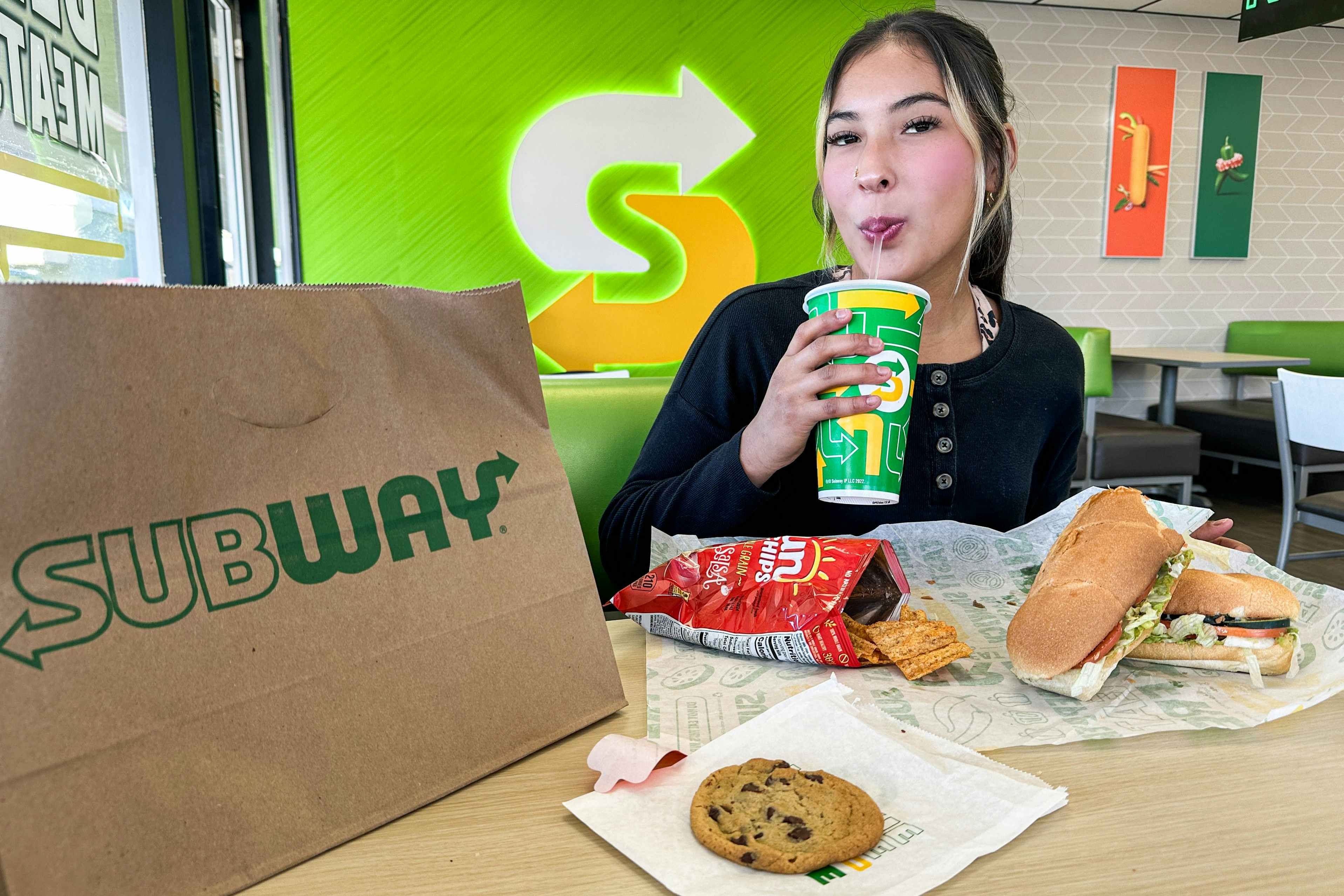 a woman taking a drink while sitting at subway