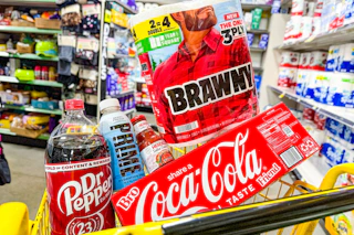 brawny, coke, dr pepper, prime, herdez products in a yellow shopping cart