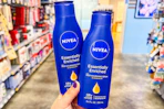 person holding 2 nivea lotions in an aisle