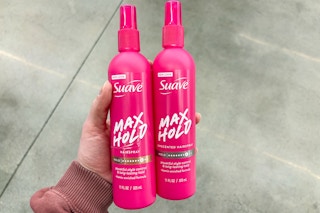 person holding 2 suave hair spray bottles