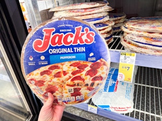 person holding a frozen pizza in the cooler