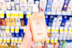 hand holding a bottle of hempz lotion in a store aisle