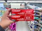 hand holding colgate toothpastes in walgreens