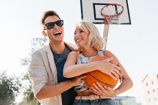 young couple playing basketball outside feature