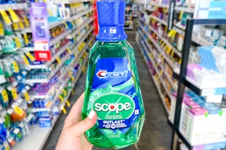hand holding a bottle of crest scope mouthwash in a store aisle