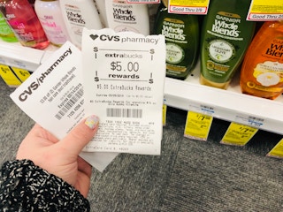 someone holding cvs extrabucks next to shampoo