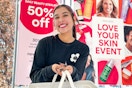 a woman holding a hand basket in front an ulta sales sign