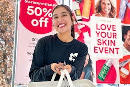 a woman holding a hand basket in front an ulta sales sign
