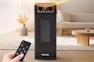 A hand points a remote at a large Tenker space heater in the middle of a beige room.