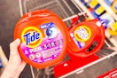 person holding a tub of tide pods over a cart with tide liquid detergent in it