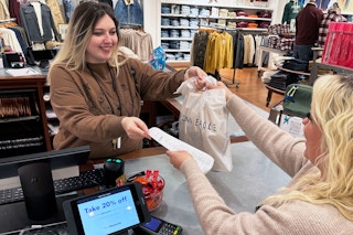 an american eagle employee giving a bag to a customer in store 