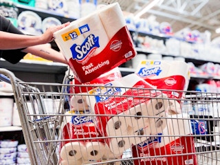 hand holding scott paper towels with five more in walmart cart