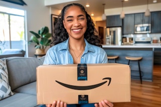 a woman holding an amazon prime delivery box in her living room