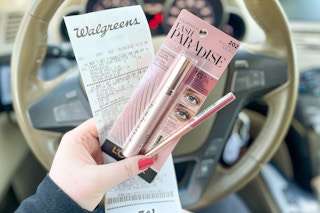 person holding loreal lash paradise mascara and a lip liner with a walgreens receipt in the car