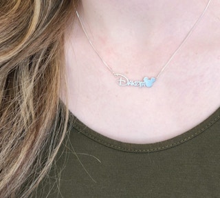 someone wearing a personalized necklace with the name emily in a disney font