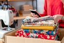 a woman in her sewing room looking at her phone and unboxing the fabric she ordered online