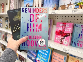 A person taking Colleen Hoover books from a shelf at Target