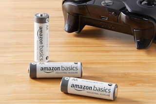 three AA batteries on a table next to a Xbox controller